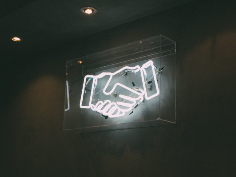 Leuchtbildreklame mit weissen Neonröhren symbolisieren einen Handschlag