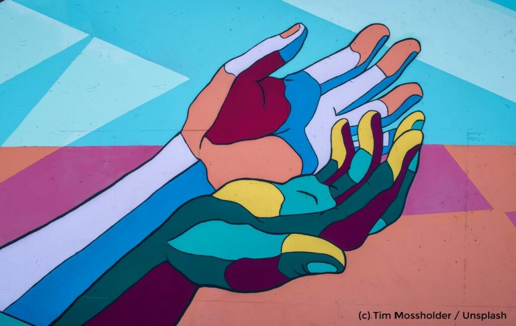 Streetart. Zwei farbige Hände umfassen sich.