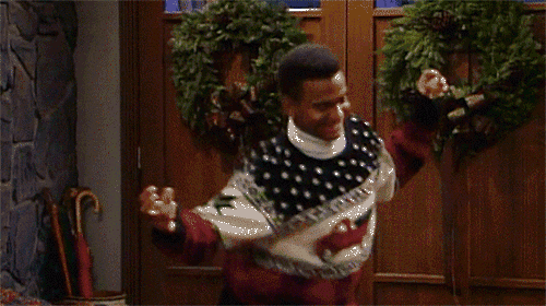 Will Smith als Prinz von Bel-AIr tanzt im Weihnachtswollpulli vor einer Tür mit Adventskranz.