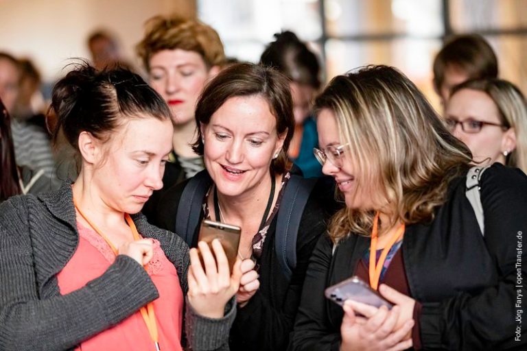 Drei Frauen schauen beim openTransfer Barcamp in Halle auf ein Smartphone. Vermutlich schauen sie sich einen neuen Post in Social Media an.
